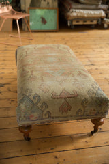 Turned wooden leg with brass caster on a vintage Turkish rug ottoman.
