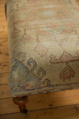 Side corner view of vintage Oushak rug ottoman with varied blue, pale yellow, and pink patterns.