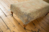 Vintage Oushak rug ottoman corner, pale yellow, pink, blue dye spots, wood leg.