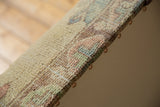 Rug ottoman edge with hand-knotted Oushak fragment, pale colors, and copper studs.