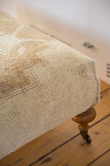 Vintage Oushak Rug Ottoman side with cream pile, hand sewn edge, and wooden caster leg.