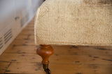 Cream and light brown Oushak rug texture, hand-sewn edge, curved wood leg, brass caster.