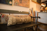 Distressed hand-knotted Turkish Oushak rug fragment lumbar pillow with earthy tones.