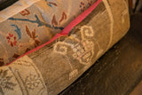 Pink fabric backing along the edge of a distressed vintage Turkish rug pillow.