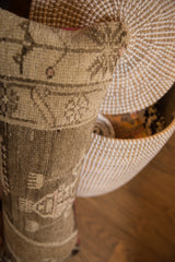 Textured vintage Oushak rug fragment pillow with muted beige and brown patterns.