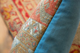 Detail of antique Belouch fragment pillow, rust-orange and blue geometric pattern, solid blue backing.