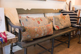 Full view of antique Belouch fragment lumbar pillow, with aged rust, orange, and blue woven design.
