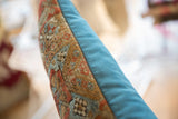 Contrasting textures on antique Belouch fragment lumbar pillow, featuring woven rug and blue backing.