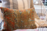 Textured detail of antique Belouch pillow, geometric rust and blue patterns, blue trim.