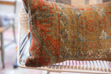 Antique Belouch fragment pillow showing textured geometric patterns in rust, blue, and earthy tan.