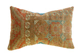 Antique Belouch rug fragment pillow, time-worn, geometric tribal patterns in rust, tan, soft teal.