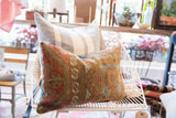 Distressed texture and tribal motifs on the antique Belouch rug fragment pillow.