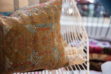 Distressed antique Belouch pillow, showing geometric tribal pattern in gold, terracotta, and blue.