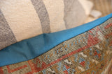 Aged Belouch rug fragment pillow with muted geometric patterns, bordered by vibrant blue fabric.