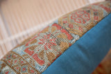 Antique Belouch rug fragment pillow with worn pile texture and geometric patterns, contrasted by teal backing.