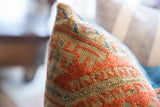 Aged hand-knotted Belouch rug fragment pillow, featuring geometric terracotta, beige, and blue patterns.