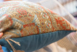 Antique Belouch rug fragment pillow edge with textured pattern and solid teal backing.