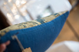Vibrant blue fabric backing texture next to beige patterned vintage Caucasian rug fragment.