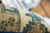 Geometric blue and cream motifs on the hand-knotted surface of a vintage Caucasian rug pillow.
