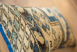 Vintage Caucasian rug pillow, textured geometric pattern in blues, ivory, black, and bright blue piping.