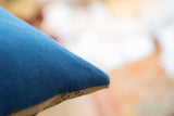Vintage rug pillow side showcasing deep blue remnant fabric and textured tan seam.