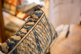 Vintage Caucasian rug pillow, angled view of blue, tan, and brown geometric texture.