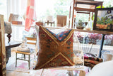 Corner detail of vintage rug fragment pillow with rich red, teal, and gold geometric pattern.