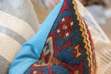 Pillow side detail, vintage rug fragment's hand-knotted texture and geometric motifs.