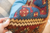 Intricate geometric pattern on vintage rug fragment pillow, featuring deep blue, red, beige.