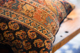 Close-up of antique Afshar rug fragment pillow featuring geometric designs in rust, indigo, gold.