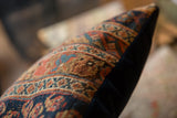 Storied Afshar tribal pattern on antique rug fragment pillow, with dark fabric backing.
