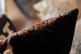 Geometric orange and deep blue Afshar rug fragment pattern bordering a dark velvet pillow backing.