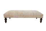 Vintage Persian Rug Ottoman Coffee Table, distressed neutral ivory and beige pattern, dark turned legs.