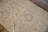 Distressed pile texture on vintage Persian rug fragment, showing faded neutral patterns.