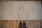 Distressed vintage Persian rug fragment surface, antique ivory and beige geometric pattern.