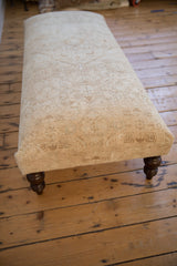 Curved dark wood leg and distressed neutral vintage Persian rug texture on ottoman.