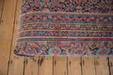 Early 20th century Persian rug fragment featuring faded red, navy, ivory, gold patterns.