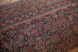Close-up of vintage Persian rug fragment, displaying rich navy, faded red, gold curvilinear motifs.