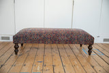 Vintage Persian Rug Ottoman with dark turned legs, intricate Persian pattern.