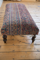 Carved dark wooden leg and corner detail of the vintage Persian rug ottoman.