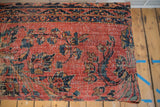 Vintage Persian rug fragment close-up: rose red, navy, gold floral, visible wear.