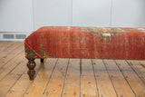 Antique Malayer rug fragment ottoman side with faded red, green geometric pattern, carved wood leg.