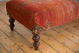 Antique Malayer rug fragment's geometric pattern on ottoman corner and turned leg.