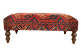 Antique Ersari rug fragment ottoman table with bold red, navy, and gold geometric patterns.