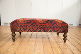 Side view of the Antique Ottoman Table, featuring bold red and navy Ersari rug fragment and turned leg.
