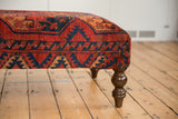 Antique Ersari rug ottoman detail, showing rich red, navy, ochre geometric patterns and turned leg.