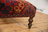 Antique Ersari rug fragment upholstery, bold red, navy geometric patterns, and turned wood leg.