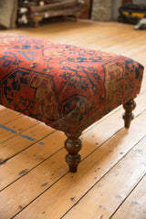 Antique Ersari rug fragment ottoman table corner, bold red and navy motifs, dark carved leg.