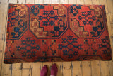 Corner of antique rug fragment ottoman table, revealing wrapped deep red and navy Ersari pattern.