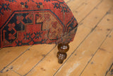 Corner of an antique Ersari rug ottoman, displaying bold red and navy geometric motifs.
